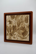 A square wooden box with a recessed interior displaying an engraved natural wood panel with abstract caterpillar-like patterns, set against a plain light gray background.
